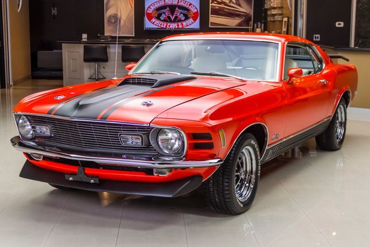 an orange muscle car parked in a showroom