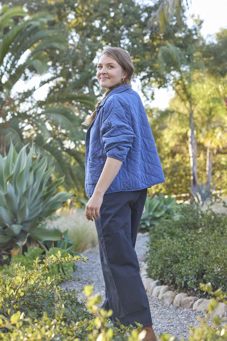 a woman standing in the middle of a garden with succulents and trees