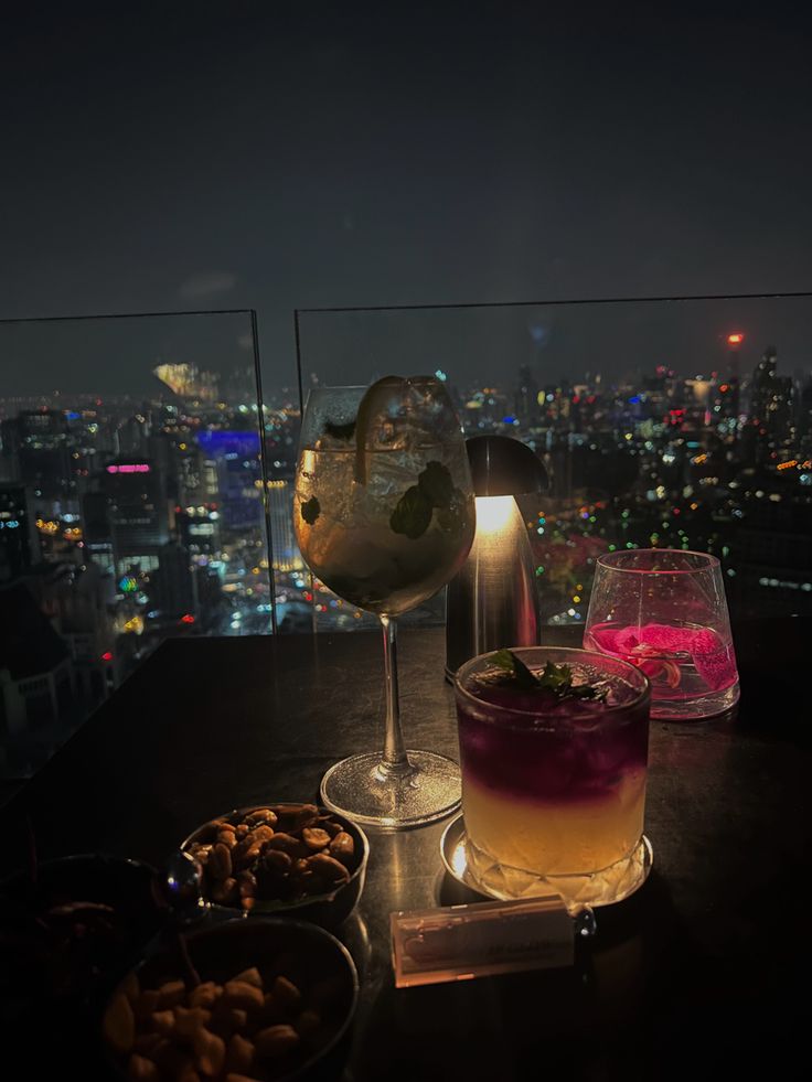 drinks and snacks on a table overlooking the city at night