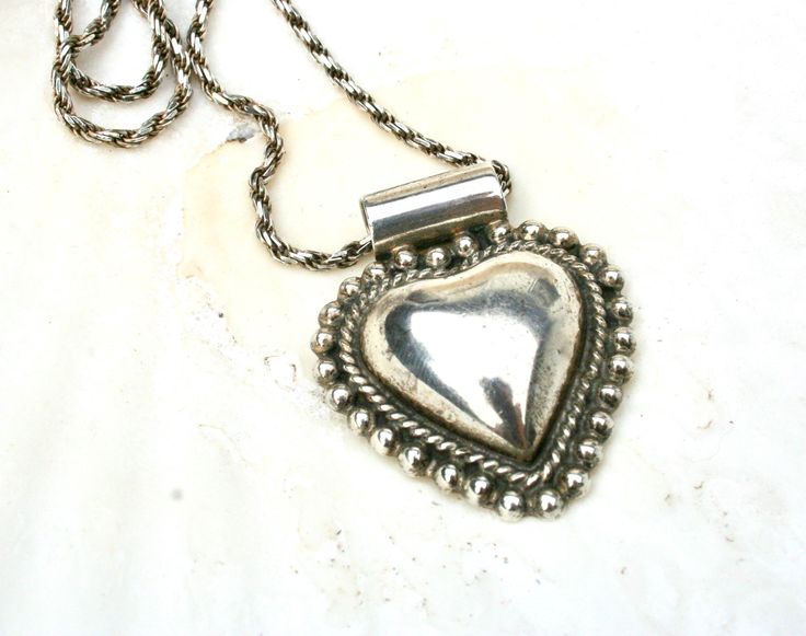 This listing is for a gorgeous sterling silver puffy heart pendant necklace. Love the presence of this piece; the three dimensionality, the detailing as well as the substantial  chain necklace.  The chain is marked 925 and Italy on the clasp, the pendant is marked 925, Mexico, ATI on the back. However, neither has been tested.  The chain measures about 29" in length, the pendant is around 1 5/8" in height and 1 3/8" in width. Both pieces are in good preowned condition with no major issues to disclose. There is some normal surface wear/scratches and tarnishing. Total weight 26 g.  For more jewelry please visit this section in my shop:  https://www.etsy.com/shop/TimeValley?ref=seller-platform-mcnav§ion_id=24958687 Necklace Love, Puffy Heart, Necklace Sterling Silver, Heart Pendant Necklace, Heart Pendant, Folk Art, Jewelry Necklace Pendant, Hand Made, Chain Necklace