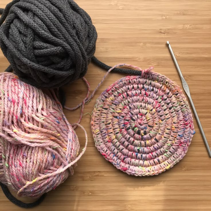 two balls of yarn and a crochet hook on a table