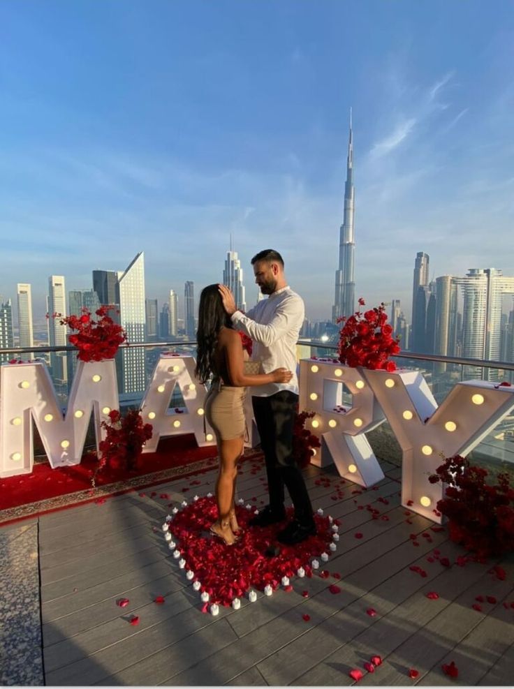 a man and woman standing in front of the word love on top of a building