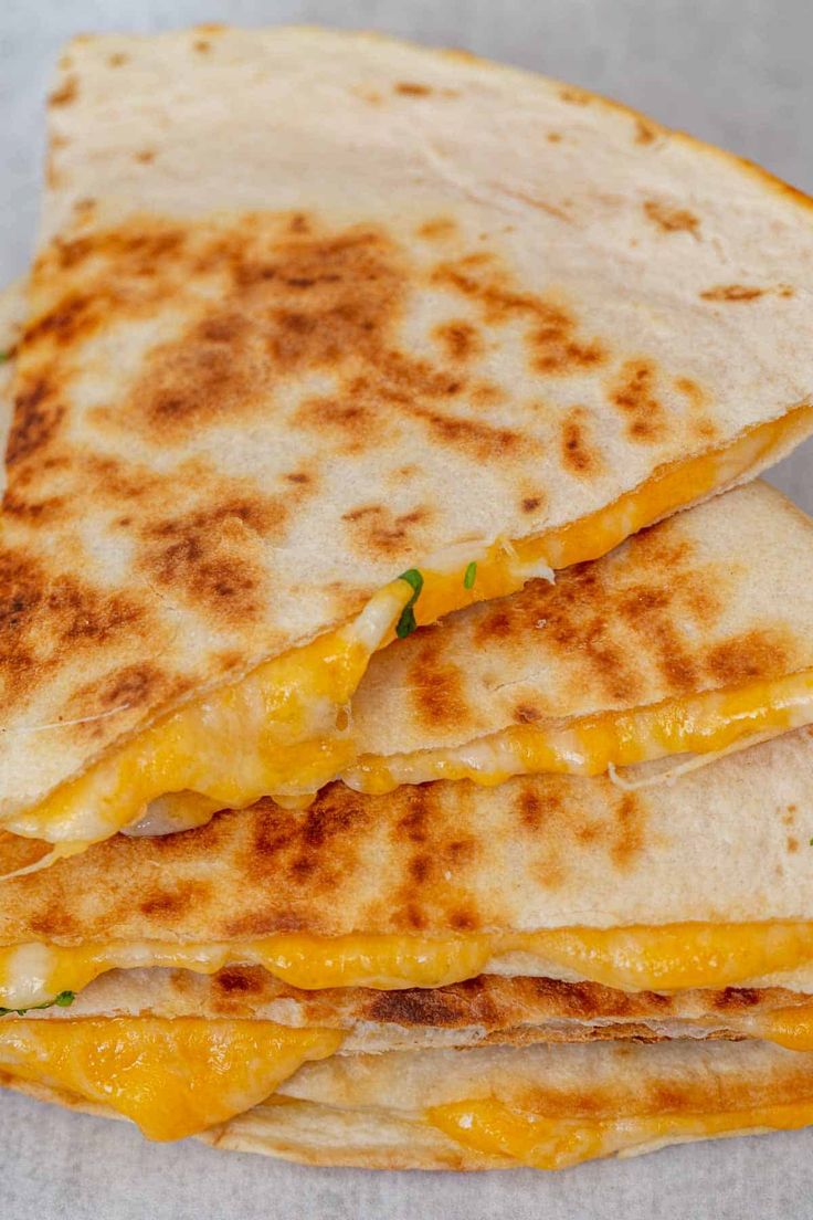 three quesadillas stacked on top of each other with cheese and melted cheese