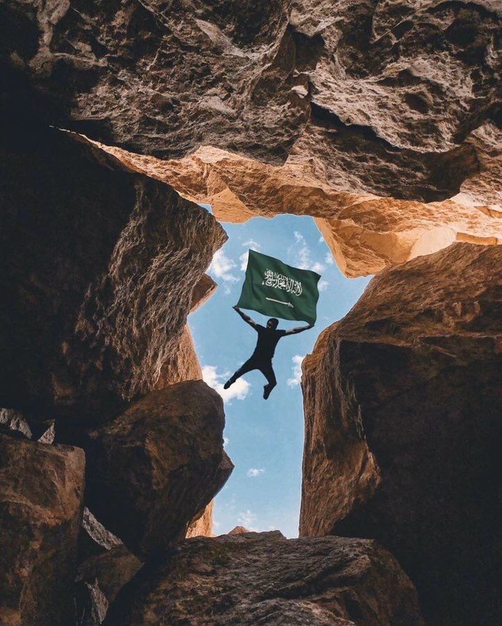 a person holding up a green sign while standing in between two large rocks on the ground