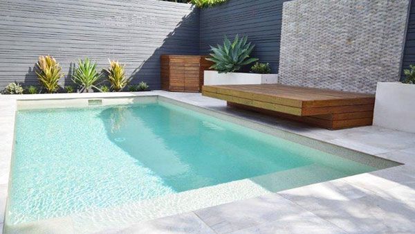 a small pool with a bench next to it in the middle of a backyard area