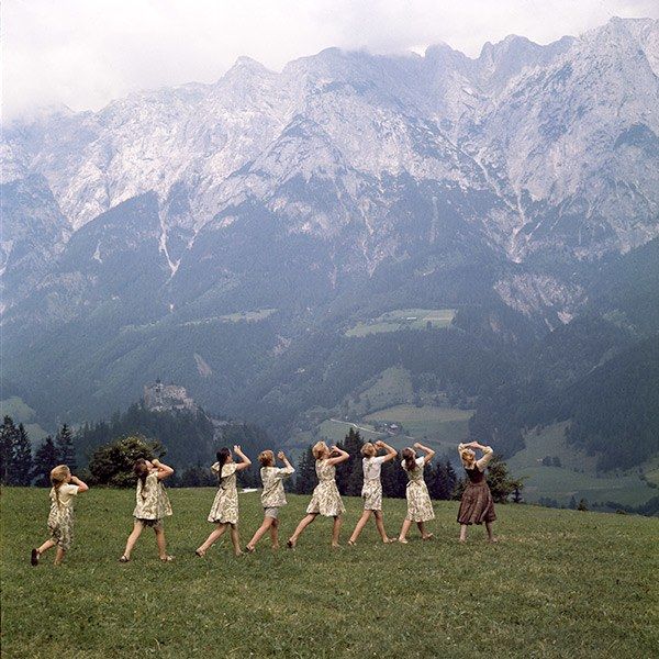 a group of women dancing in the grass with mountains in the background