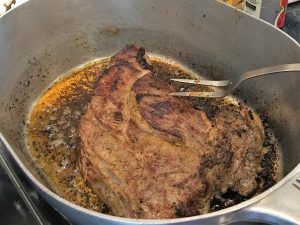 a steak is being cooked in a pan on the stove with a fork sticking out of it