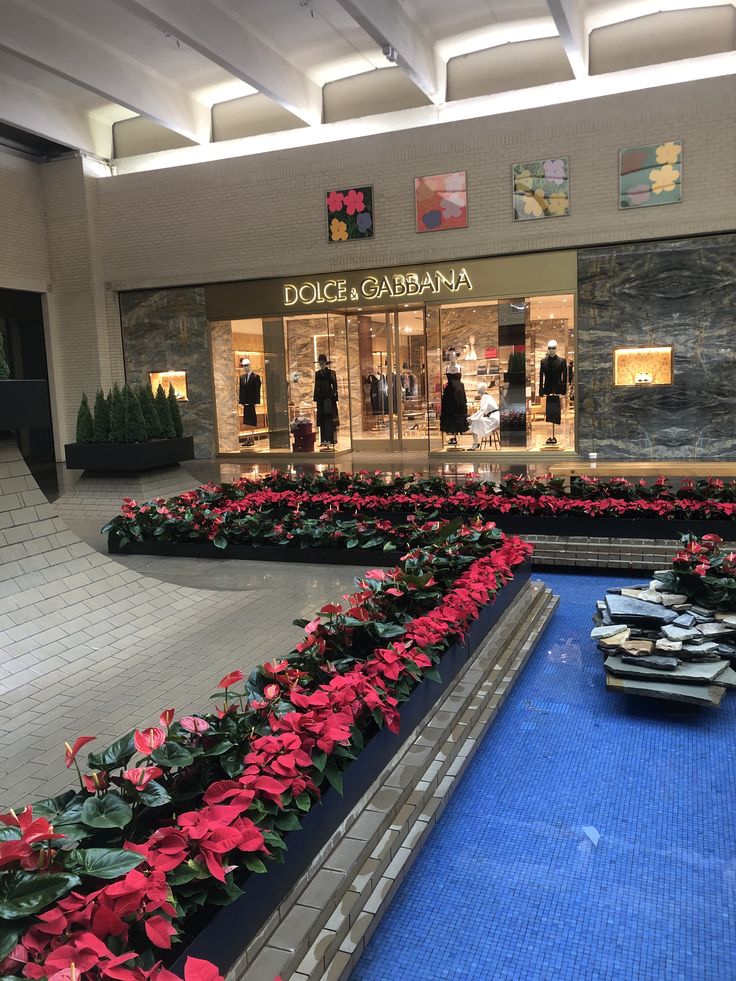 the inside of a shopping mall with christmas decorations and flowers on display in front of it