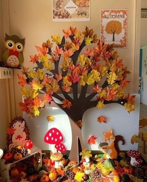 a table topped with plates covered in autumn leaves and mushrooms next to an owl figurine