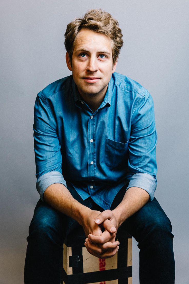 a man sitting on top of a box with his hands in his lap and looking at the camera