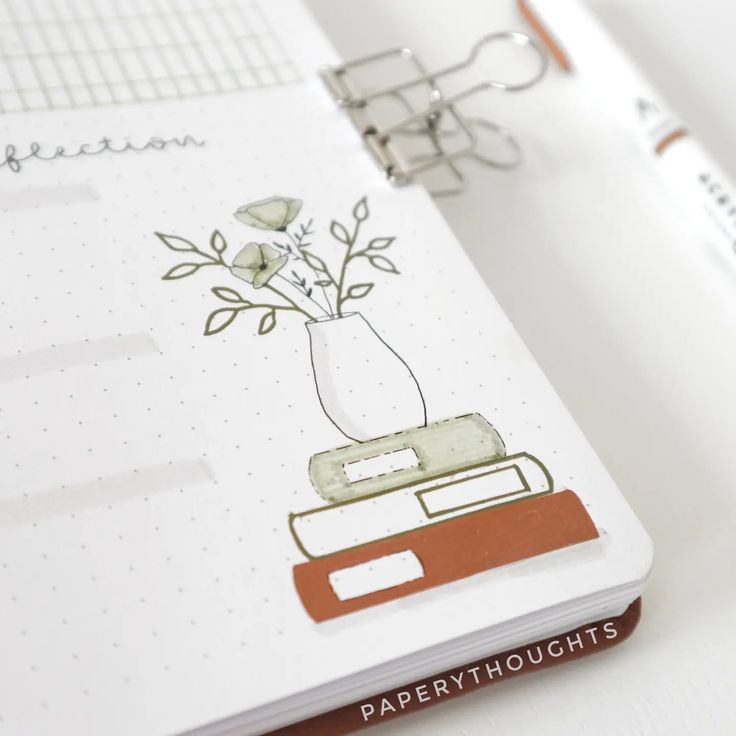 an open notebook with a flower in a vase