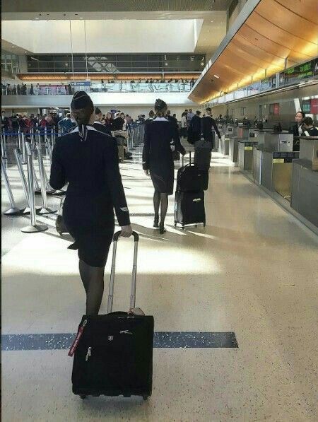 people walking through an airport with luggage on their back and one person pulling a suitcase behind them