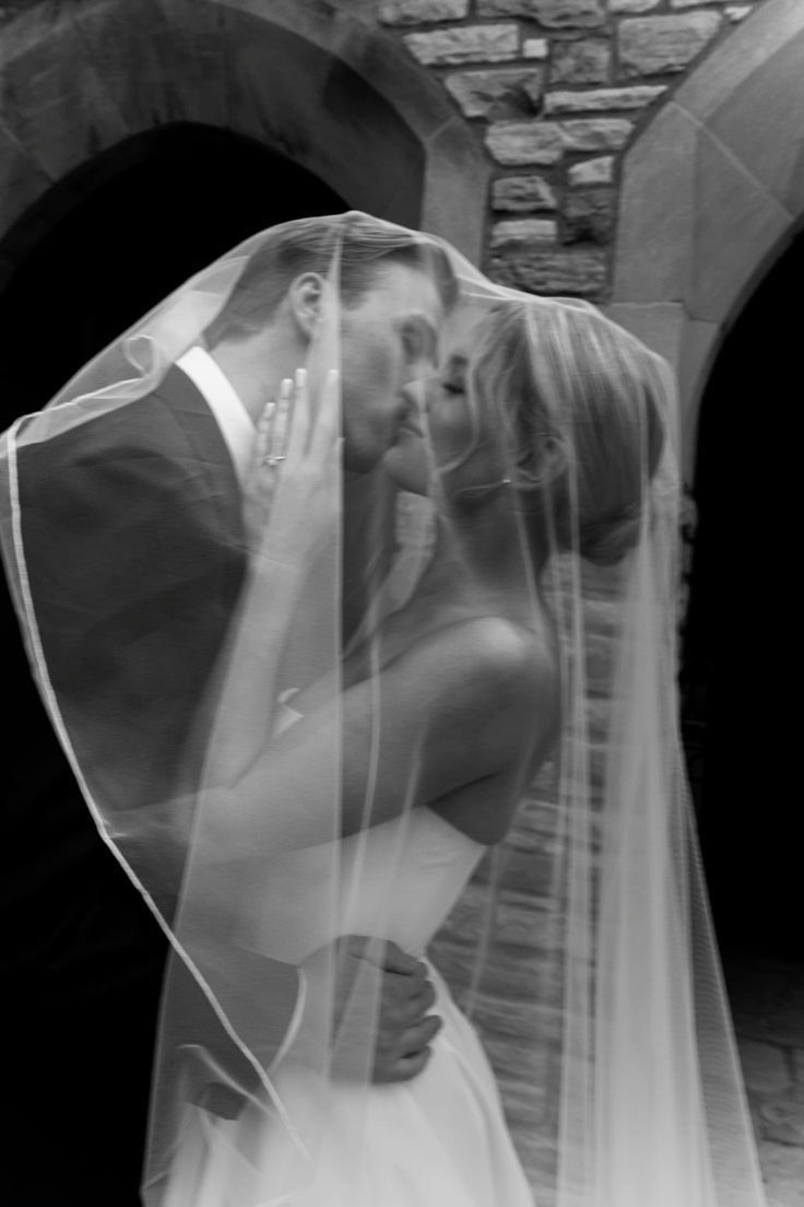 a bride and groom kissing under a veil