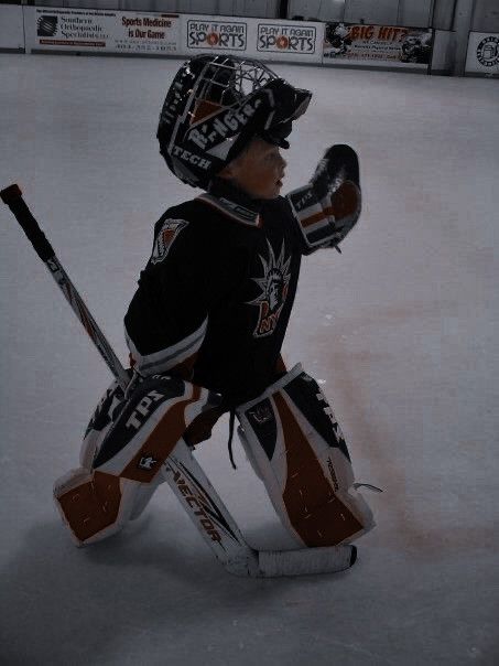 a hockey goalie sitting on the ice waiting for the next play