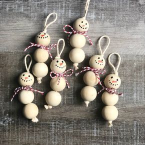 six snowman ornaments hanging from string on wooden table with red and white twine