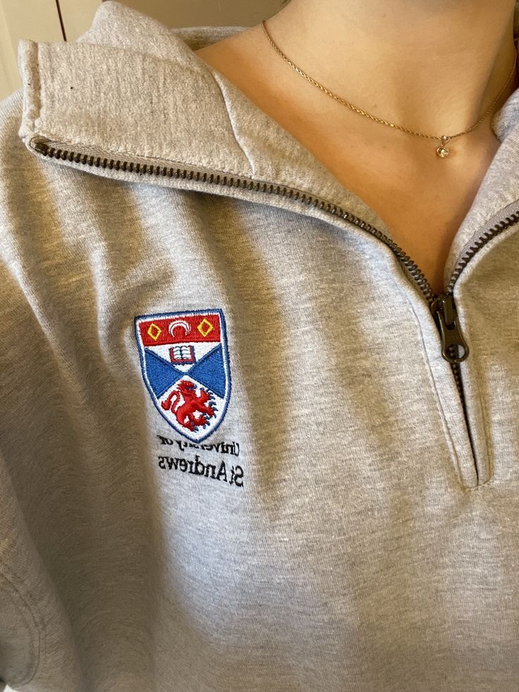 a woman wearing a gray shirt with a red and blue crest on it's chest