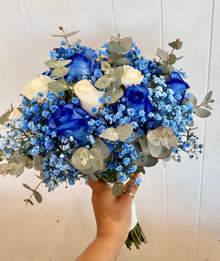 a hand holding a bouquet of blue and white flowers