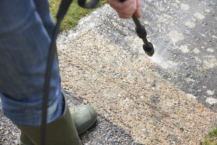 a person using a power tool to clean the pavement