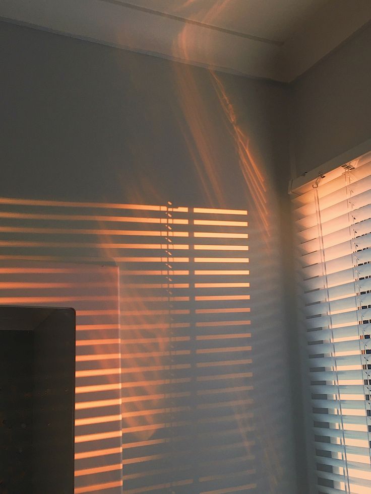 the sun is shining through blinds in a room