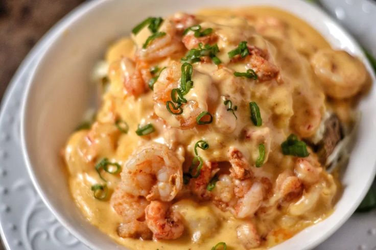 a white bowl filled with shrimp and grits covered in sauce on top of a table