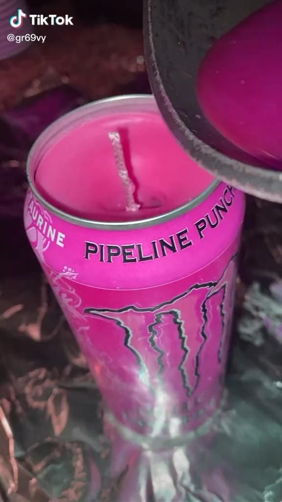 a pink candle with the words pipeline punch printed on it next to a cup filled with liquid