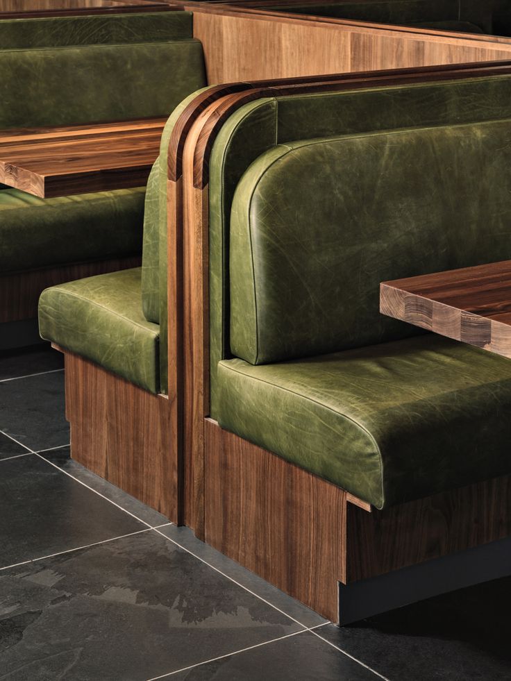 two green chairs sitting next to each other on top of a tiled floor in a restaurant