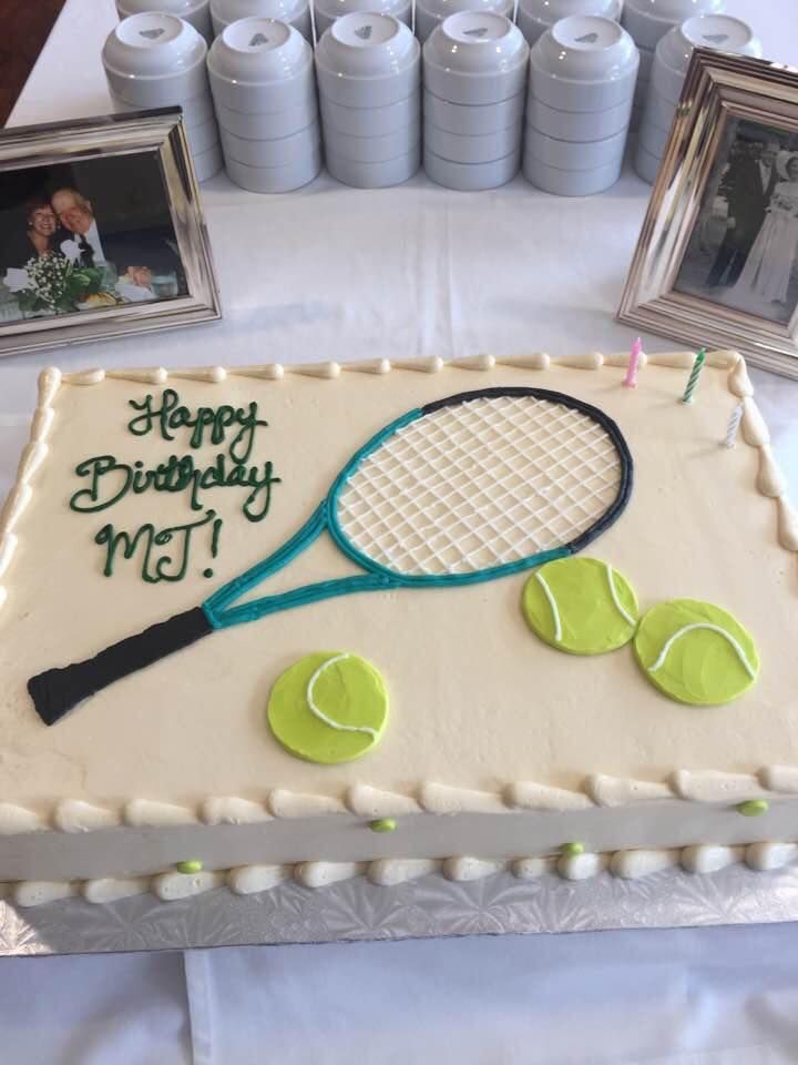 a birthday cake with a tennis racket and balls on the table next to it