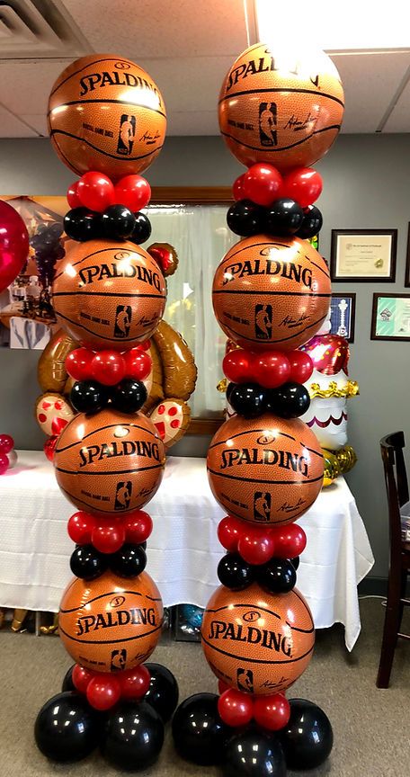 some basketballs are stacked on top of each other in front of a table with balloons