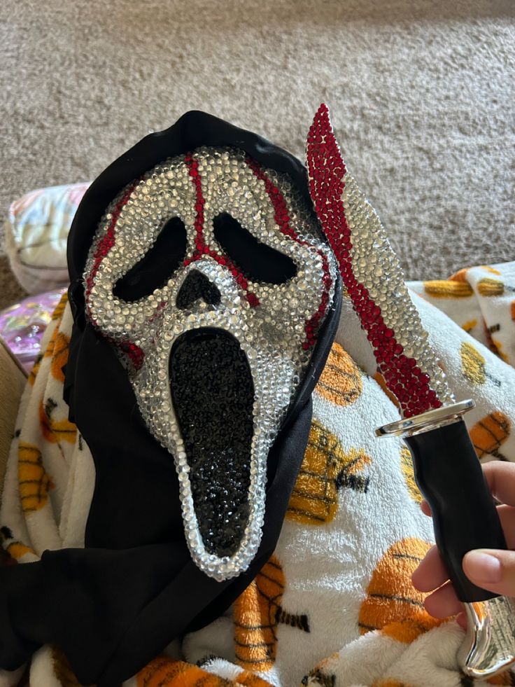 someone is holding a knife in front of a cloth covered object with a scream mask on it