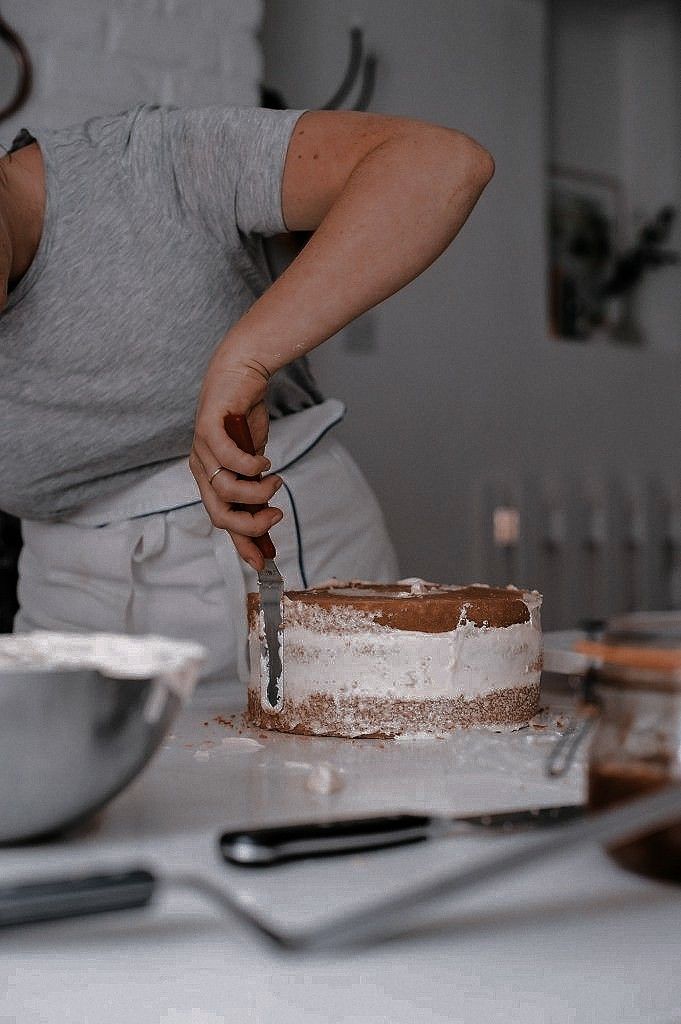 a woman cutting a cake with a knife on top of it in front of other plates and utensils