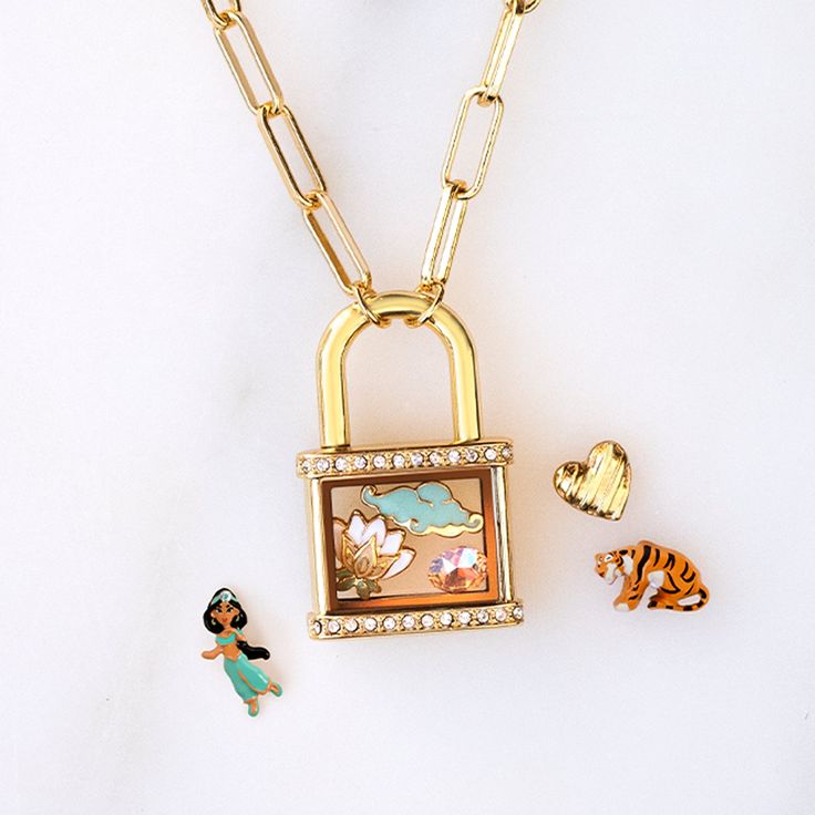 a gold chain necklace with a lock and charms attached to it, sitting on a white surface