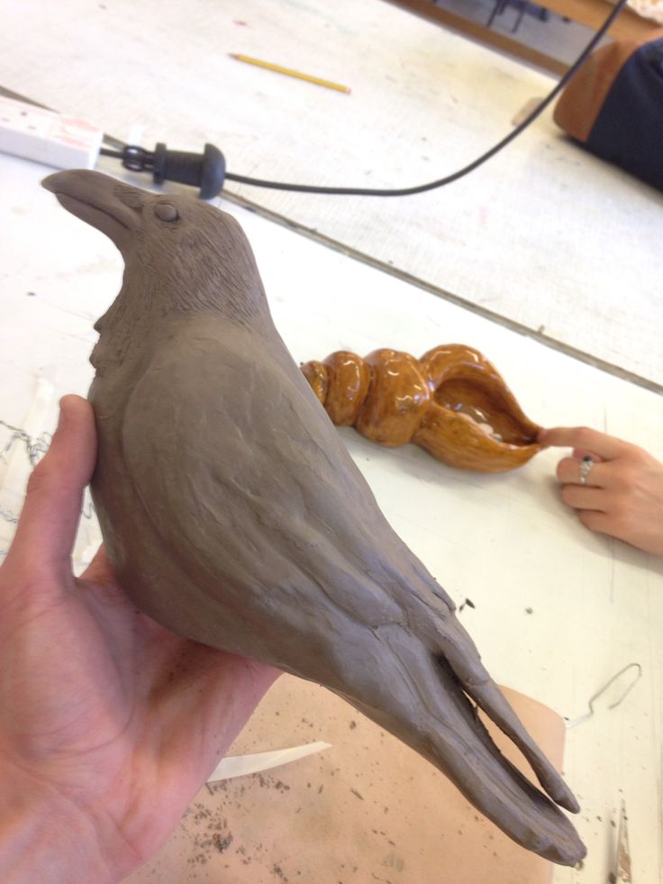 a person is holding a clay bird in their hand and it looks like they are making something out of clay