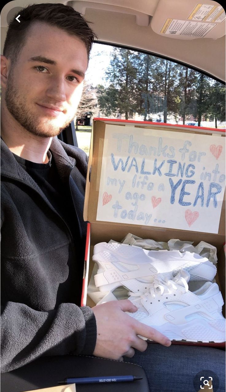 a man sitting in the back seat of a car holding an open shoe box with writing on it