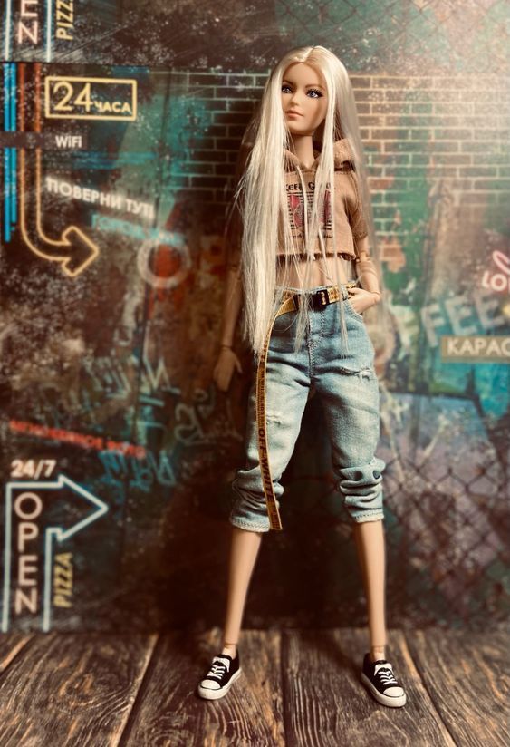 a doll with long white hair standing in front of a brick wall and wearing jeans