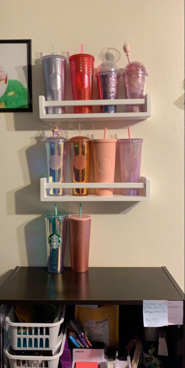 there are many cups on the shelf above the desk and in front of the wall