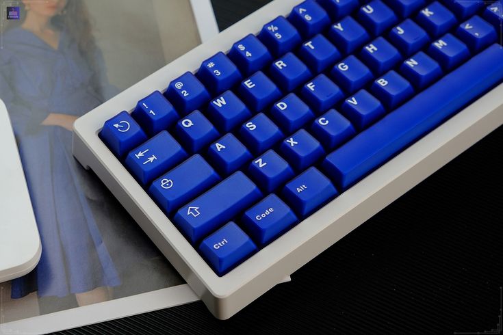 a blue computer keyboard sitting on top of a table next to a mouse and monitor