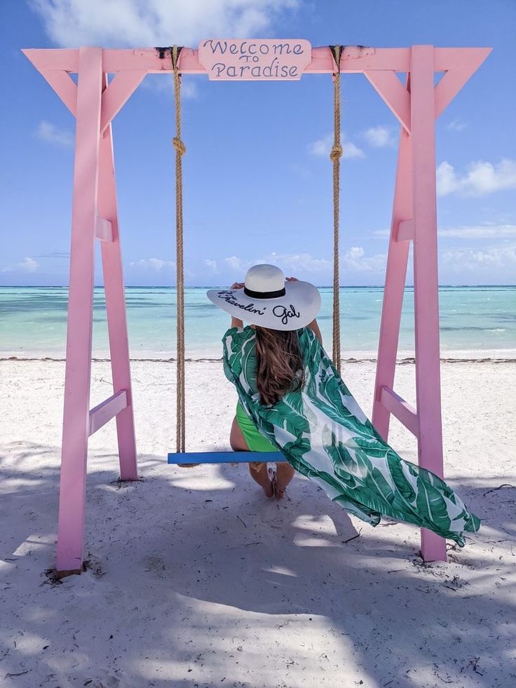 a woman sitting on a swing at the beach