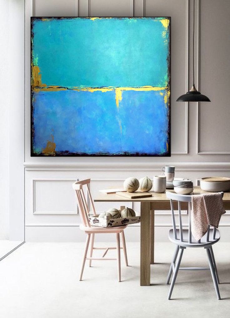 a painting is hanging on the wall above a table with two chairs in front of it