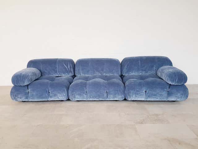 a blue couch sitting on top of a hard wood floor next to a white wall