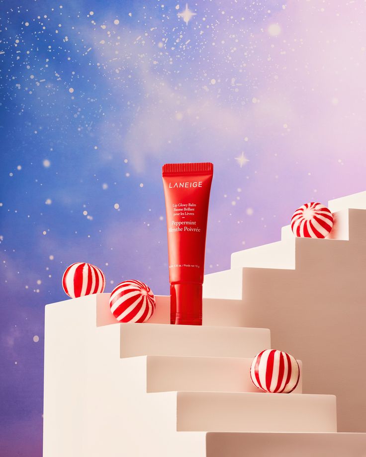 a tube of sunscreen sitting on top of a set of white steps with red and white striped balls