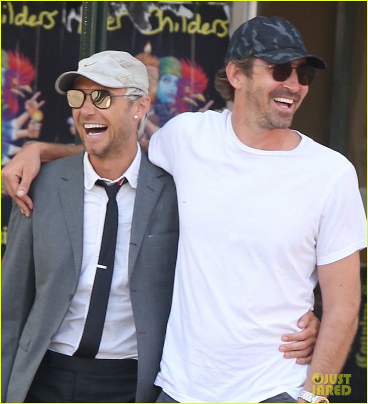 two men standing next to each other in front of a store with their arms around one another