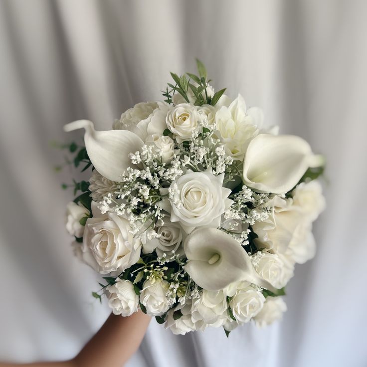 a bridal bouquet with white roses and baby's breath