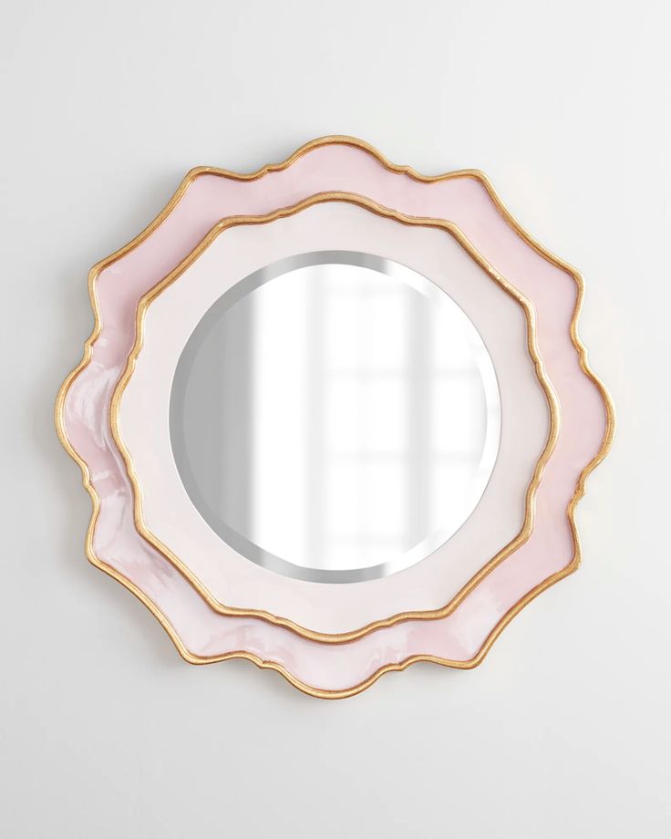 a pink and gold mirror on the wall