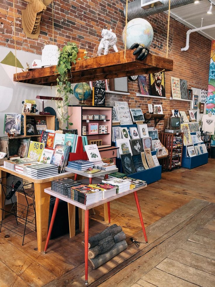 a room filled with lots of books on top of a wooden floor next to a brick wall