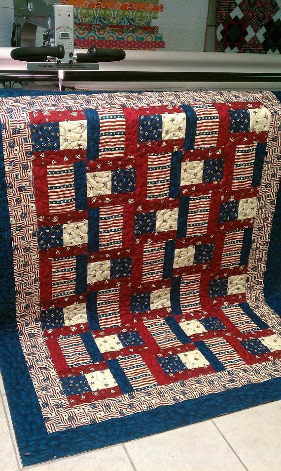 a red, white and blue quilt sitting on top of a table next to a sewing machine