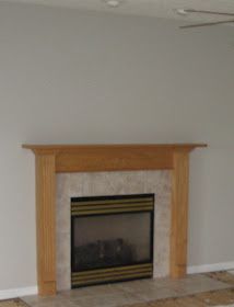 an empty living room with a fireplace and tile floor