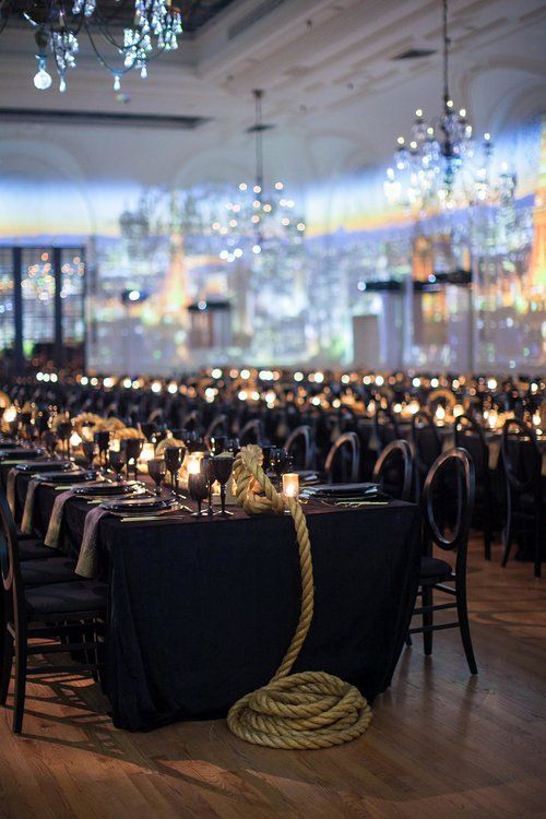 a room filled with lots of tables covered in black cloths and lit up candles