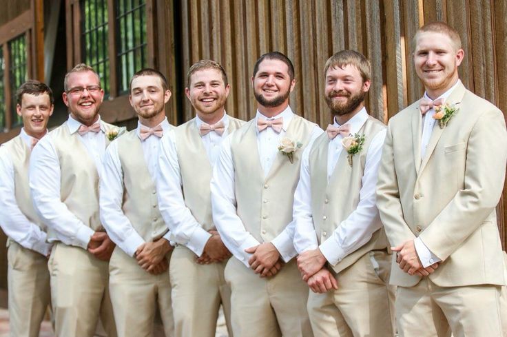 a group of men standing next to each other wearing tan suits and bow ties on their wedding day