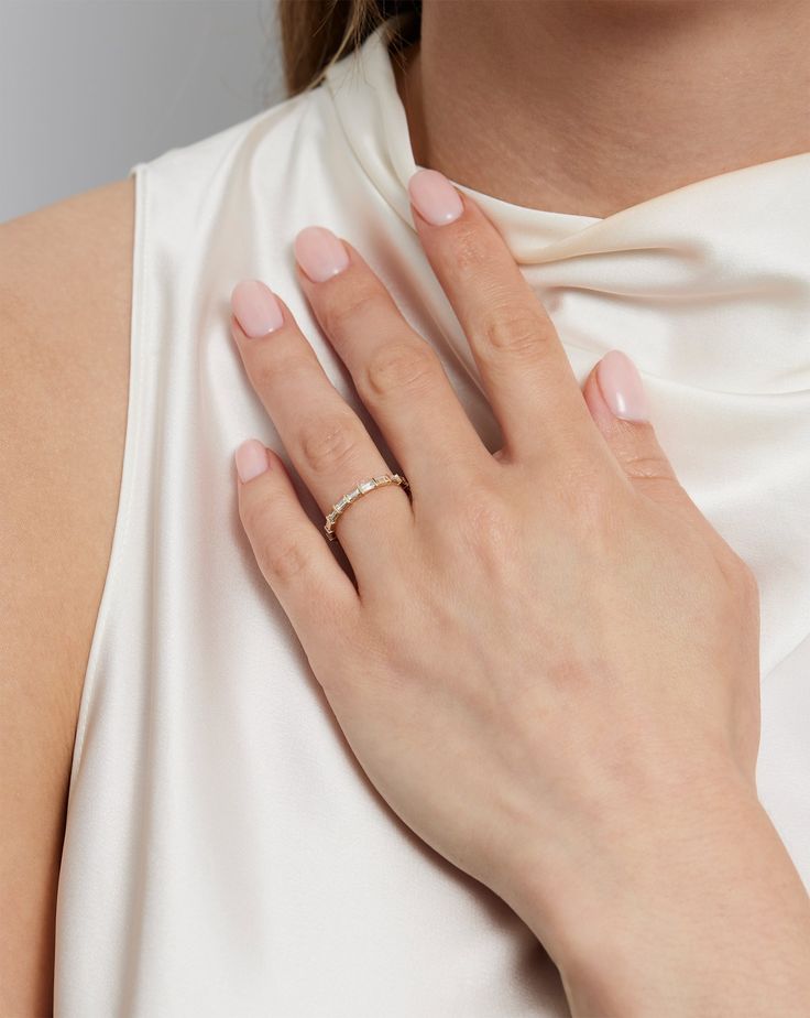 a woman wearing a white dress with a gold ring on her left hand