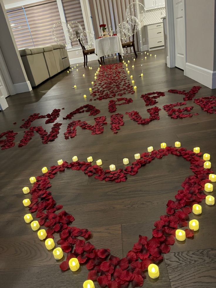 a heart - shaped sign made out of flowers and candles in the middle of a room